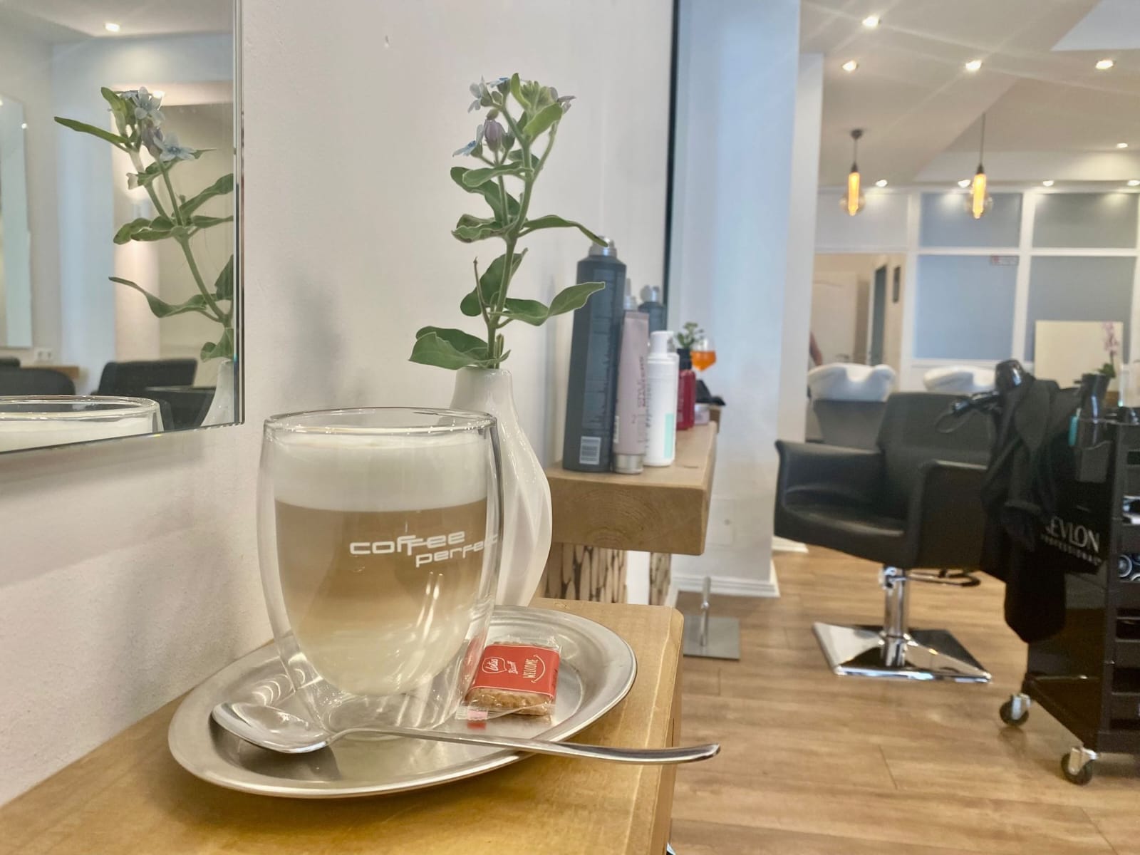 Blick in den Salon. Im Vordergrund steht ein Glas mit Latte Macchiato.